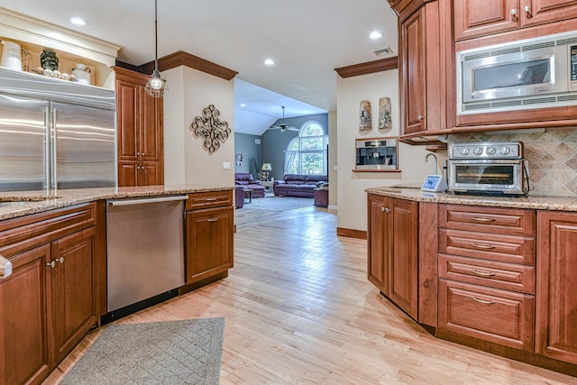 34 Clark Ln, Harriman, NY 10926 - kitchen with built in appliances, light wood finished floors, brown cabinetry, vaulted ceiling, and decorative backsplash
