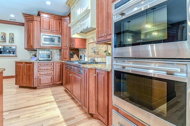 34 Clark Ln, Harriman, NY 10926 - kitchen featuring stainless steel appliances, light wood-style floors, light stone countertops, tasteful backsplash, and brown cabinets
