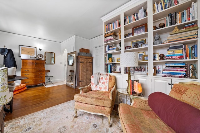 sitting room featuring arched walkways, ornamental molding, and wood finished floors