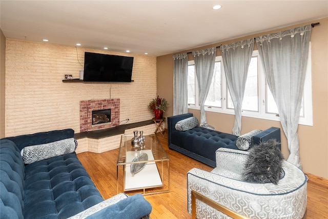 living room with a brick fireplace, brick wall, wood finished floors, and recessed lighting