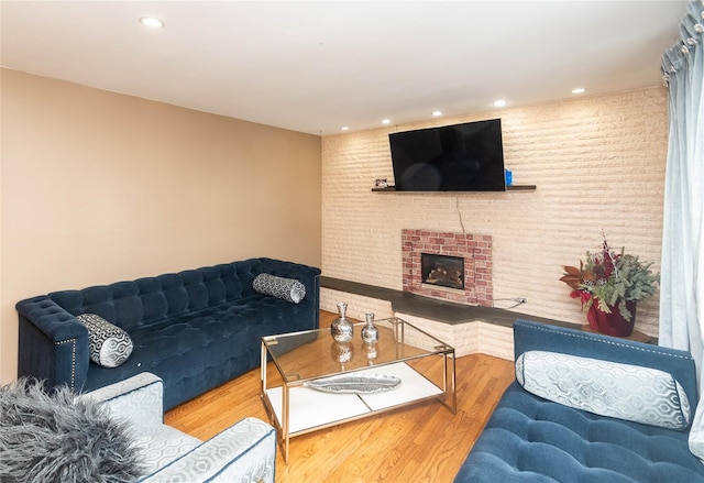 living room with a brick fireplace, wood finished floors, and recessed lighting