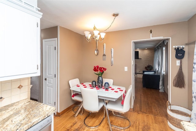 dining room with a chandelier, light wood finished floors, and baseboards