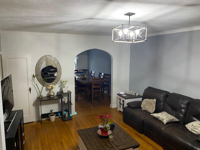 living room featuring ornamental molding, hardwood / wood-style floors, a textured ceiling, and a chandelier