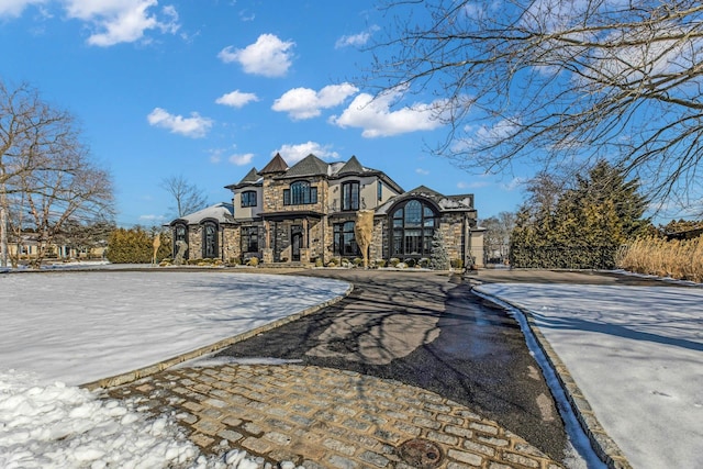 french country style house featuring stone siding and aphalt driveway