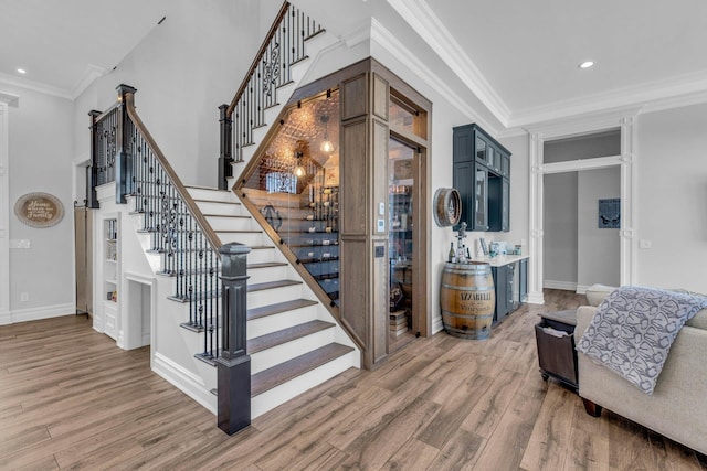 interior space featuring recessed lighting, a high ceiling, wood finished floors, baseboards, and ornamental molding