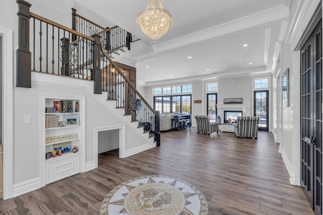 entryway featuring ornamental molding, a glass covered fireplace, dark wood-style flooring, and stairs