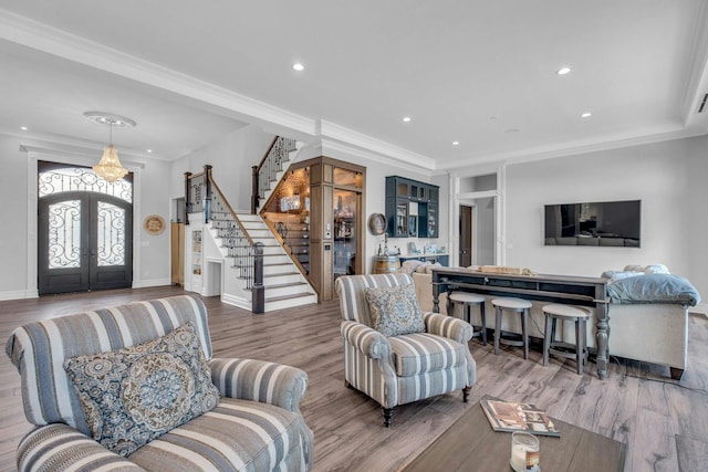 living area with stairway, ornamental molding, wood finished floors, and french doors