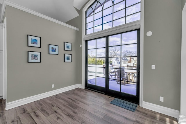 doorway to outside featuring light wood-type flooring, baseboards, and crown molding