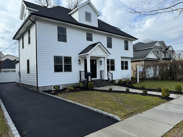 view of front of house with an outbuilding, a front yard, and a detached garage