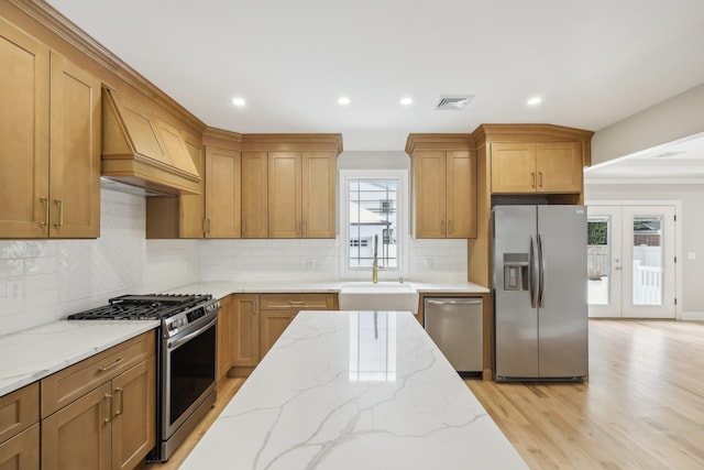kitchen featuring custom exhaust hood, visible vents, appliances with stainless steel finishes, a sink, and light wood-type flooring