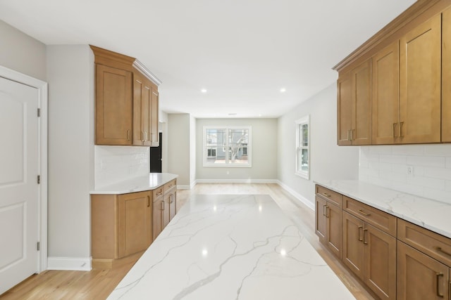 kitchen with brown cabinetry, decorative backsplash, and light stone countertops