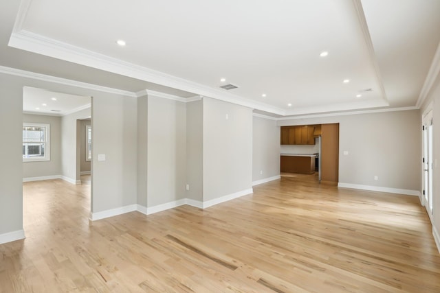 unfurnished room with light wood-style flooring, a raised ceiling, visible vents, and baseboards