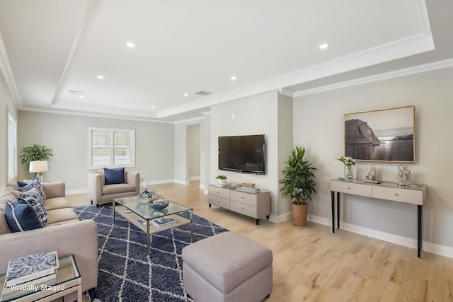 living room with a raised ceiling, crown molding, and light wood finished floors
