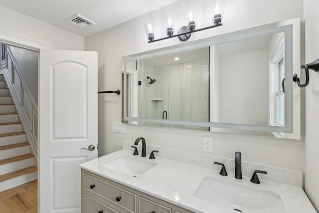 bathroom featuring double vanity, a stall shower, a sink, and visible vents