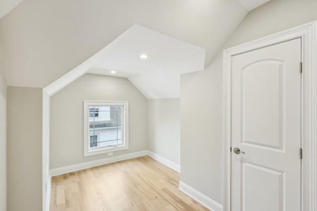 additional living space featuring light wood-style flooring, baseboards, and vaulted ceiling