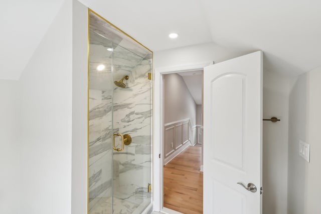 bathroom featuring lofted ceiling, a marble finish shower, wood finished floors, and recessed lighting