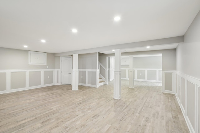 finished below grade area featuring recessed lighting, a decorative wall, stairway, and light wood finished floors