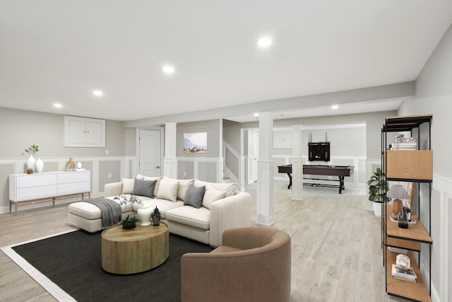 living room with light wood-style floors, recessed lighting, a decorative wall, and stairway