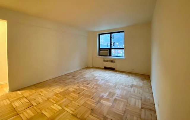 unfurnished room with radiator heating unit and light parquet floors