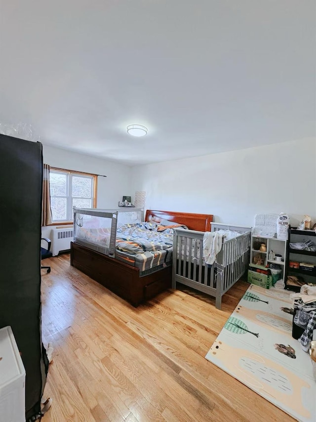 bedroom with radiator and light wood-type flooring