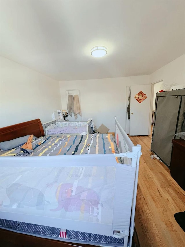bedroom with wood-type flooring and stainless steel fridge