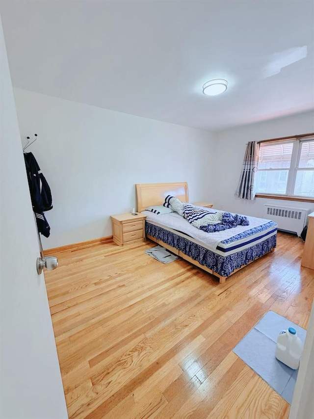 bedroom featuring radiator and hardwood / wood-style flooring