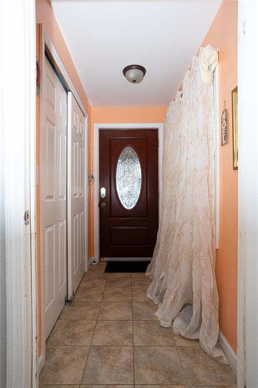 entryway with baseboards and light tile patterned floors