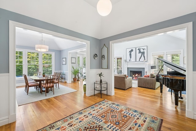 9 Owls Nest Ln, East Hampton, NY 11937 - living area featuring vaulted ceiling, wood finished floors, wainscoting, and a lit fireplace