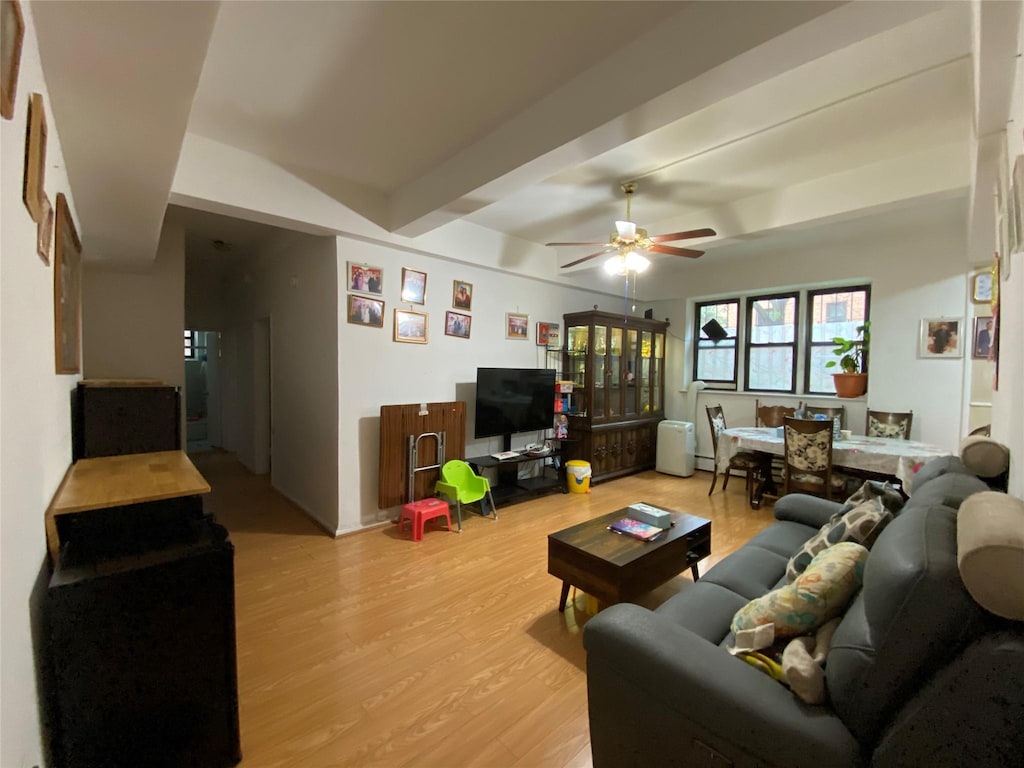 living room featuring ceiling fan, beam ceiling, and light wood-type flooring