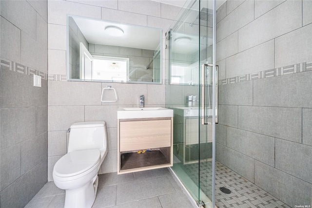 bathroom featuring tile patterned flooring, vanity, a shower with shower door, and toilet