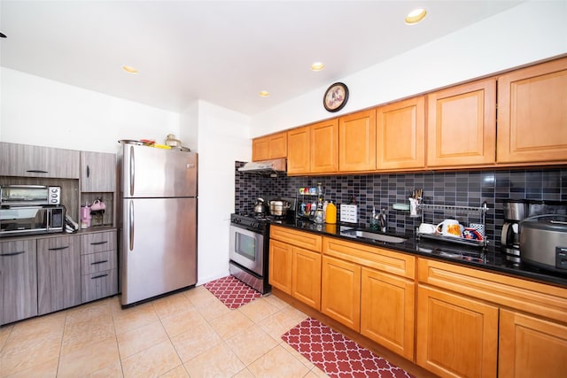 kitchen featuring sink, light tile patterned floors, appliances with stainless steel finishes, dark stone counters, and backsplash