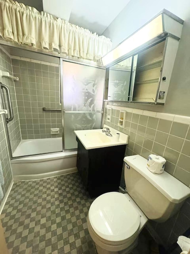 full bathroom with enclosed tub / shower combo, toilet, tile walls, and vanity