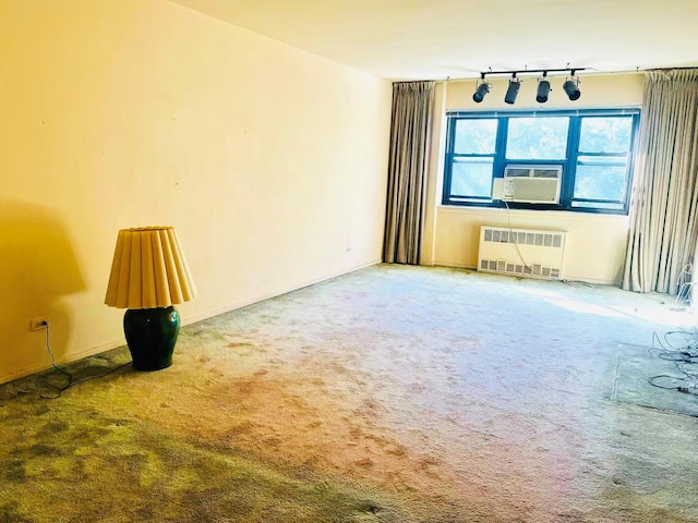 carpeted spare room featuring radiator, track lighting, and cooling unit