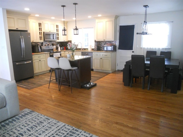 kitchen featuring appliances with stainless steel finishes, a center island, hanging light fixtures, and a breakfast bar area