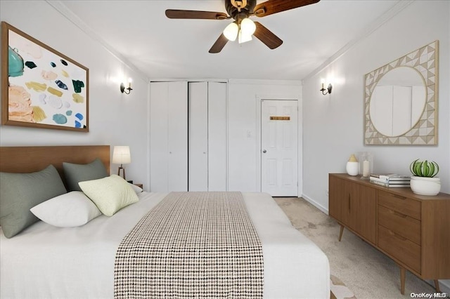 bedroom featuring ornamental molding, light colored carpet, ceiling fan, and a closet