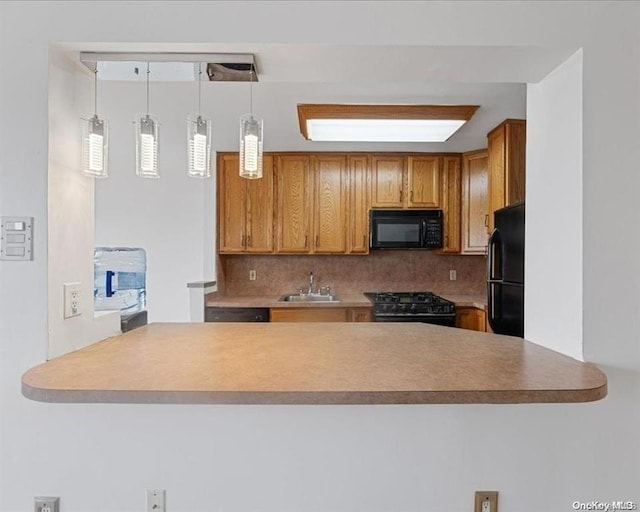 kitchen with pendant lighting, kitchen peninsula, sink, and black appliances