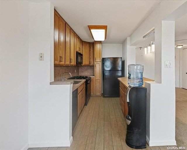 kitchen featuring tasteful backsplash, sink, black appliances, and light wood-type flooring