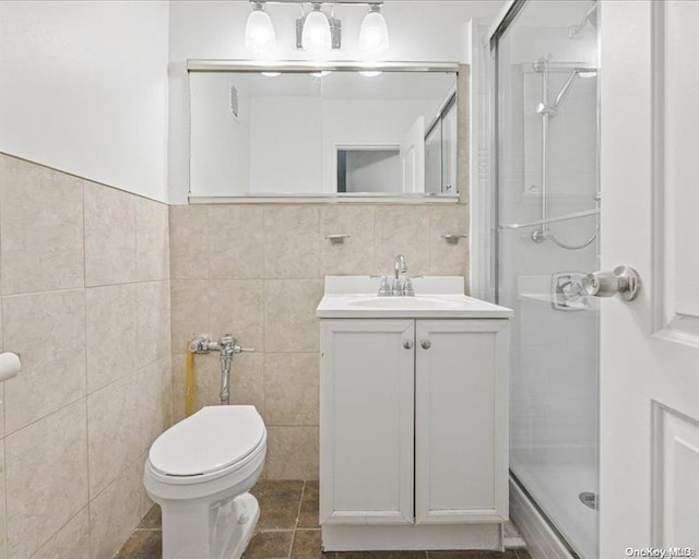 bathroom with tile walls, vanity, an enclosed shower, toilet, and tile patterned floors