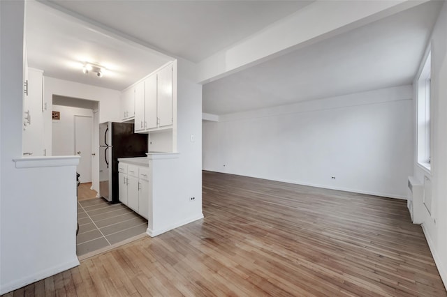 kitchen with stainless steel fridge, light hardwood / wood-style floors, and white cabinets