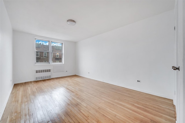 spare room featuring radiator and light hardwood / wood-style floors