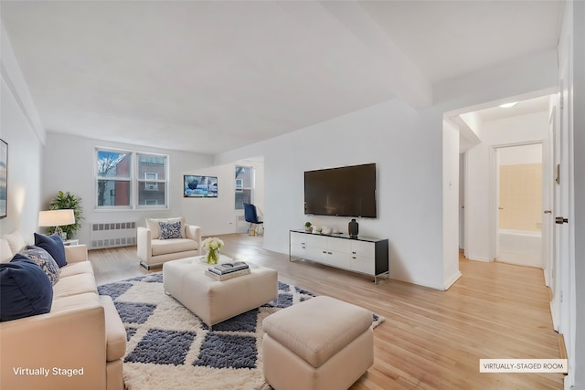 living room with light hardwood / wood-style flooring, beam ceiling, and radiator heating unit