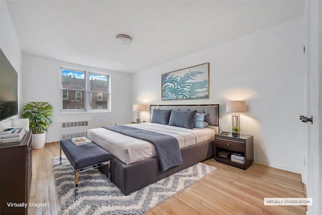 bedroom featuring radiator and light hardwood / wood-style flooring