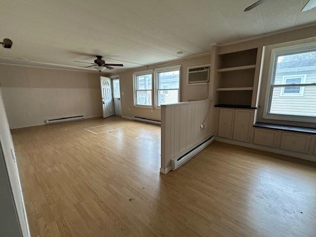 spare room featuring light wood finished floors, baseboard heating, a ceiling fan, and a baseboard radiator