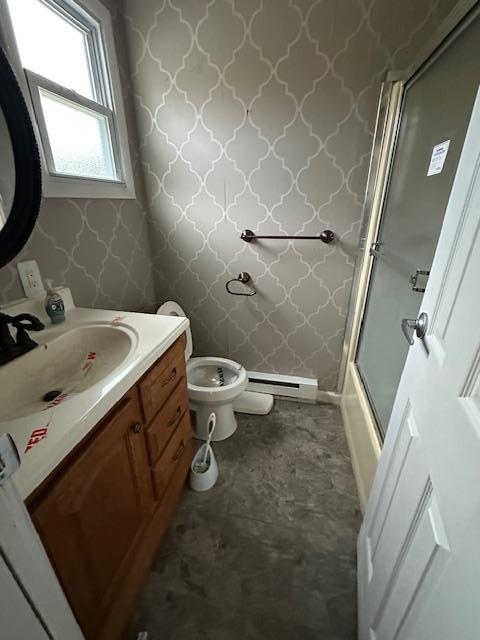 bathroom featuring wallpapered walls, toilet, baseboard heating, enclosed tub / shower combo, and vanity