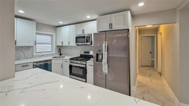 kitchen featuring white cabinetry, sink, backsplash, light stone counters, and stainless steel appliances