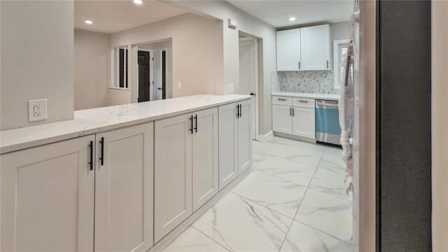 kitchen featuring white cabinetry, light stone counters, kitchen peninsula, stainless steel appliances, and decorative backsplash