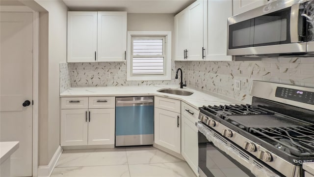 kitchen featuring sink, white cabinetry, light stone counters, tasteful backsplash, and appliances with stainless steel finishes