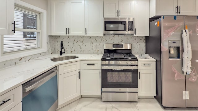 kitchen featuring white cabinetry, stainless steel appliances, light stone countertops, and sink