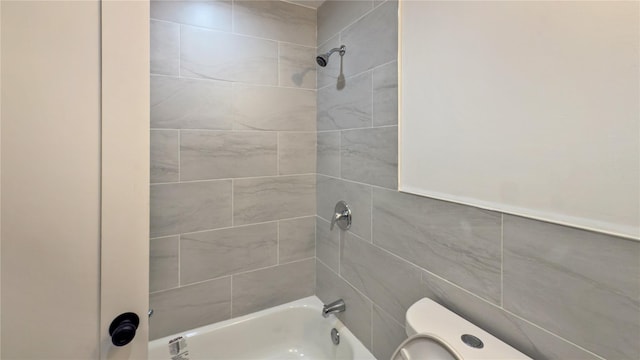 bathroom with tiled shower / bath combo and toilet