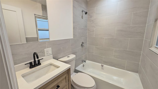 full bathroom featuring tiled shower / bath, vanity, toilet, and tile walls